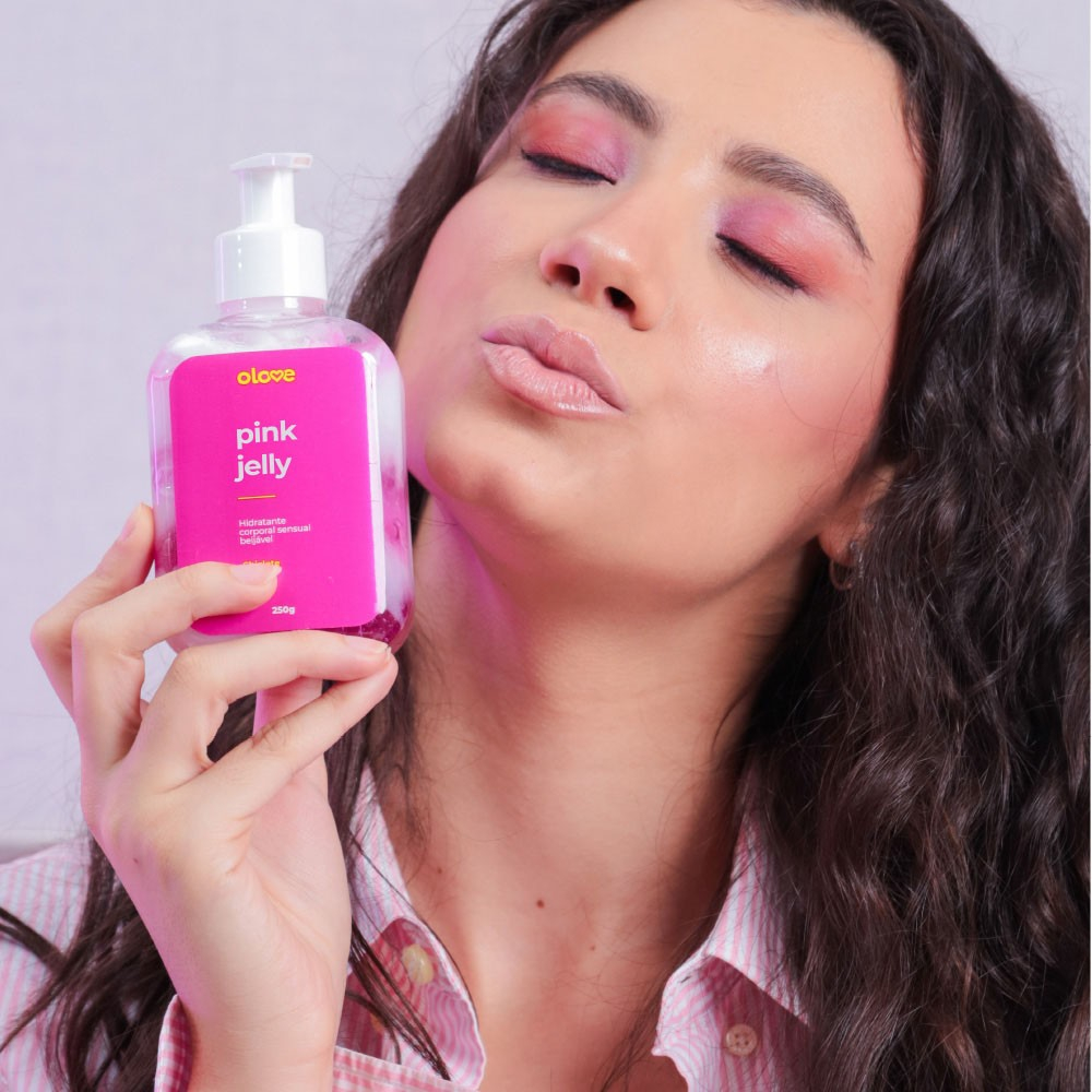 Mulher com maquiagem rosa e olhos fechados, segurando o frasco do Gel Hidratante Corporal Sensual Pink Jelly Sabor Chiclete, com express�o de prazer