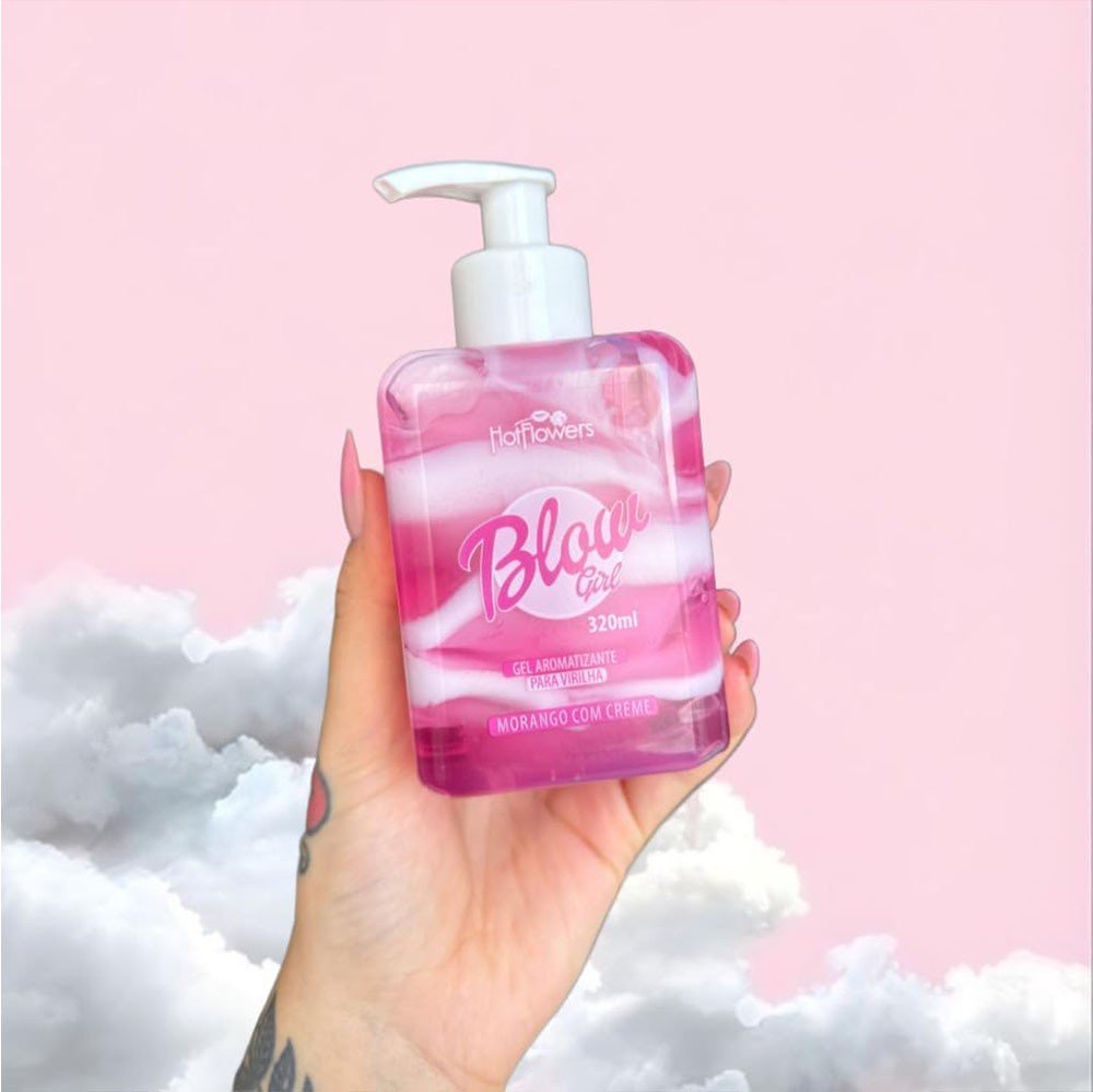 M�o de mulher segurando o frasco do Gel Hidratante para Virilha Blow Girl Aroma Morango com Creme, destacando o gel em tons de rosa e branco, com fundo cor-de-rosa e nuvens