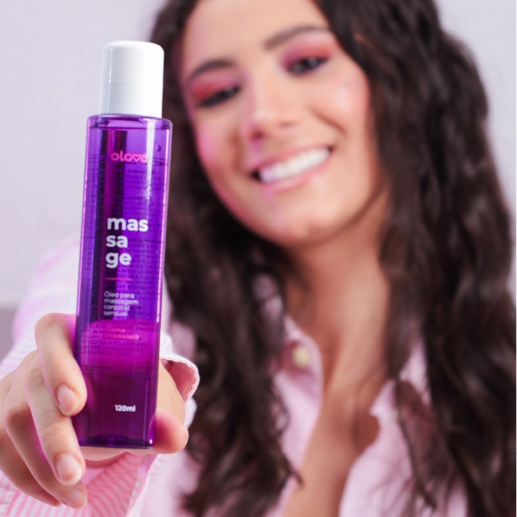 Mulher sorrindo segurando frasco roxo de �leo para Massagem Sensual Massage da Olove Cosm�tico, 120ml, em foco