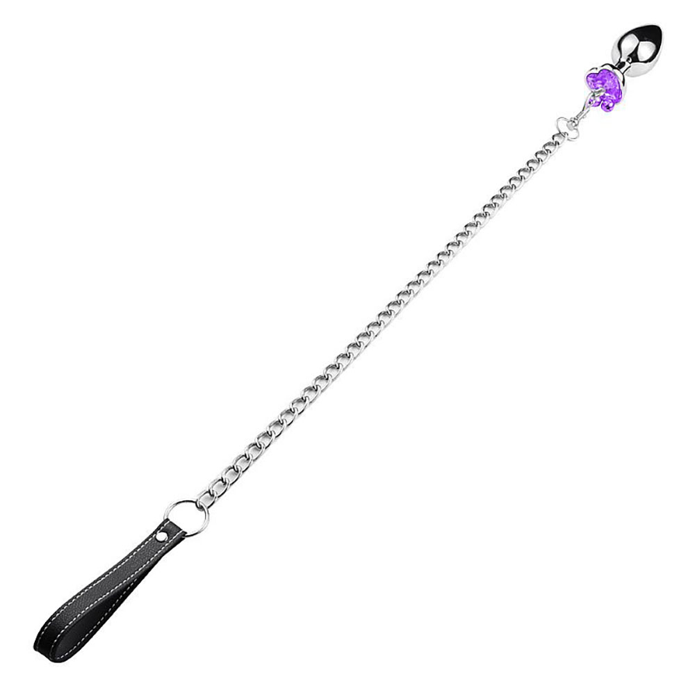 Vis�o completa do Plug Anal Joia em A�o Inox, com o cristal roxo e sinos, conectado � corrente e guia com al�a de couro preta, estendido em fundo branco.