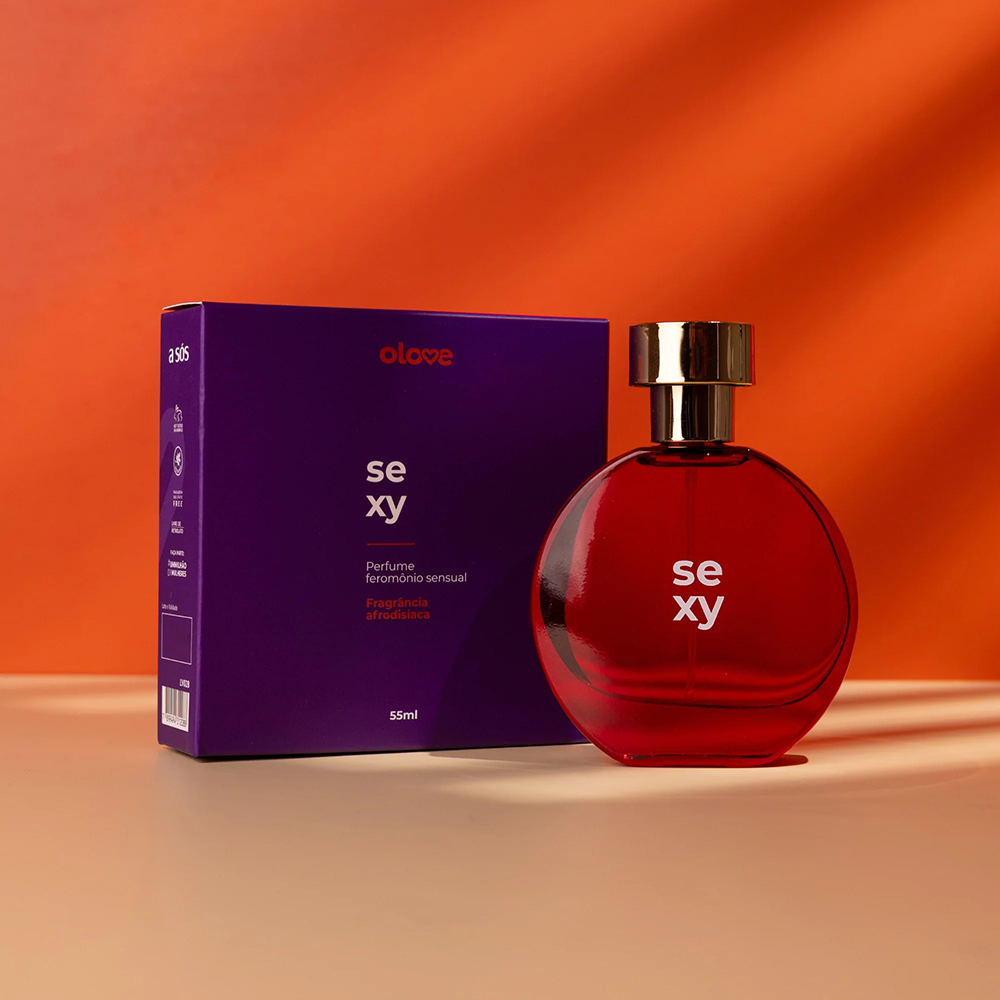 Frasco de perfume Olove Sexy 55ml na cor vermelha com tampa dourada ao lado da caixa roxa, em ambiente sensual