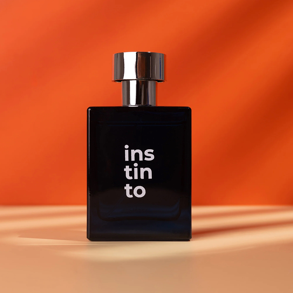 Frasco do perfume Olove Instinto azul escuro com tampa prata em fundo laranja