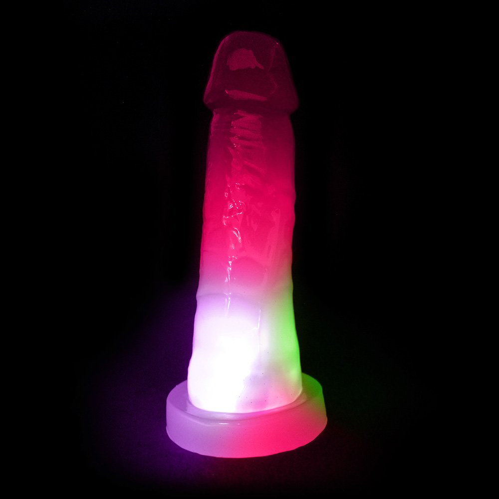 P�nis Pisca Pisca Mi�rcoles com Base para Cinta Transl�cido Rosa em destaque, com as luzes de pisca-pisca ativadas em ambiente escuro, mostrando as cores rosa, verde e branco