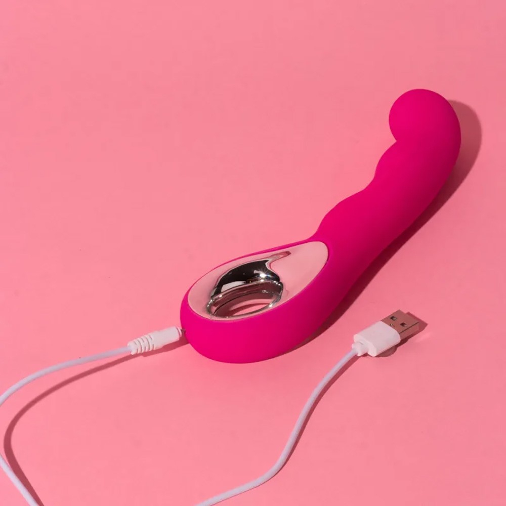 Vibrador Ponto G Recarreg�vel em Silicone Rosa sendo carregado via USB, em fundo rosa