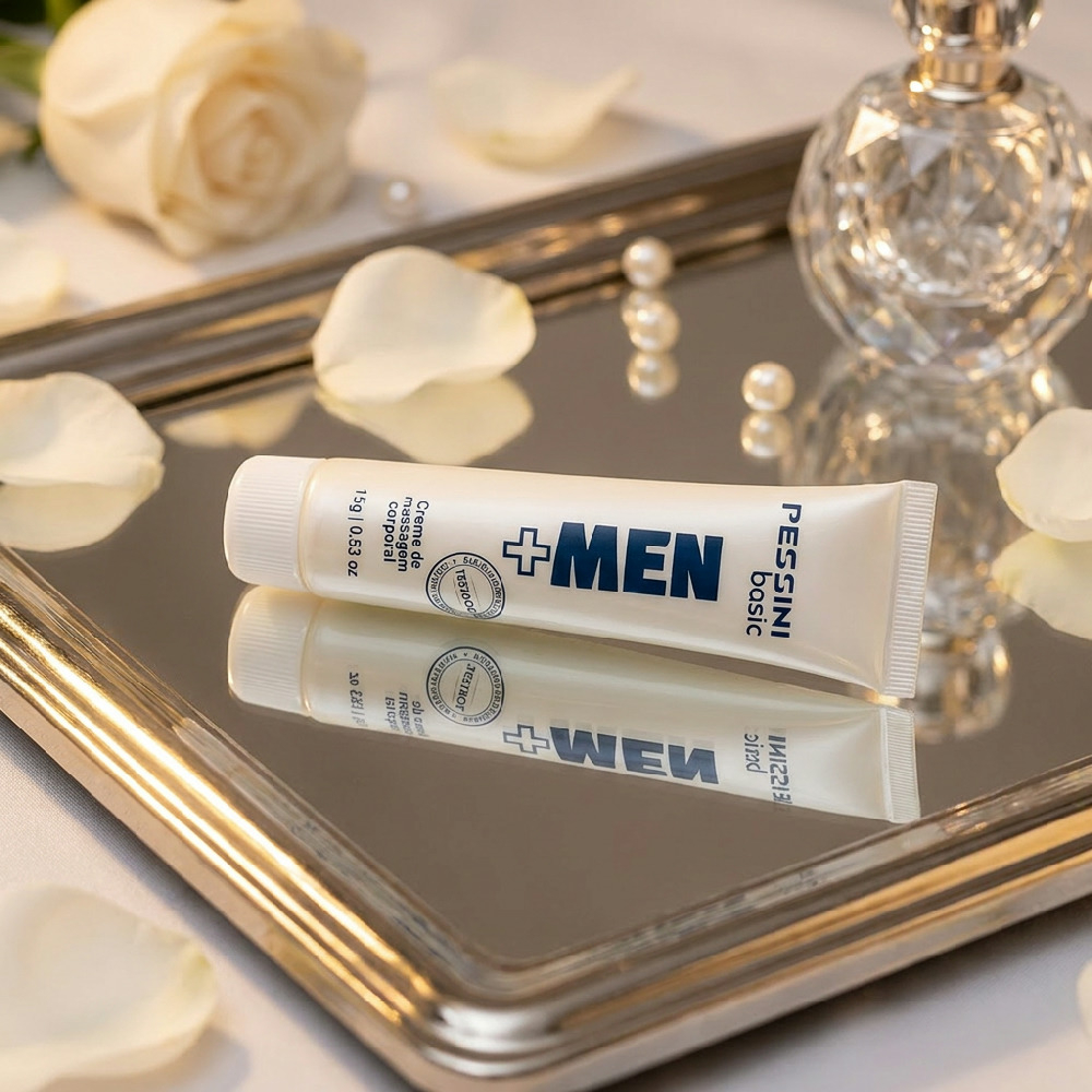 Tubo do Gel Excitante Masculino + MEN 15g, sobre uma bandeja espelhada, com p�talas de rosa brancas e p�rolas ao redor. O tubo est� refletido na bandeja.