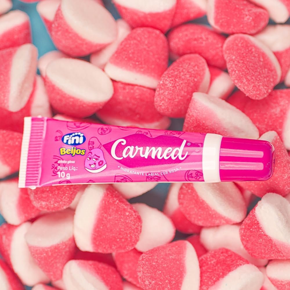Hidratante Labial Carmed Fini Beijos, tubo do produto sobre balas Fini Beijos