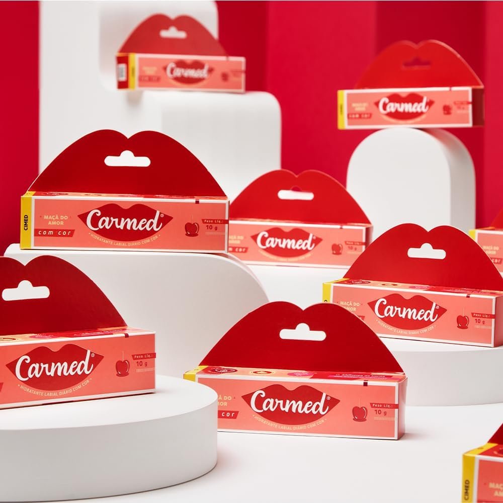 Tubo do Carmed Ma�� do Amor com Cor e a caixa aberta ao fundo, evidenciando o design e a marca Cimed.