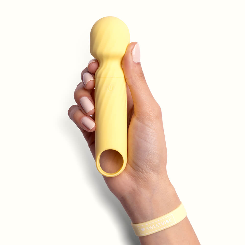 Mulher segurando o Massageador Er�tico Dengo Amarelo, demonstrando o tamanho e ergonomia na m�o