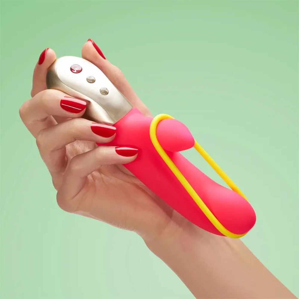 Vibrador Duplo em Silicone Recarreg�vel Amorino Pink em uma m�o feminina, exibindo o bra�o externo amarelo em contraste com o silicone pink e a base metalizada