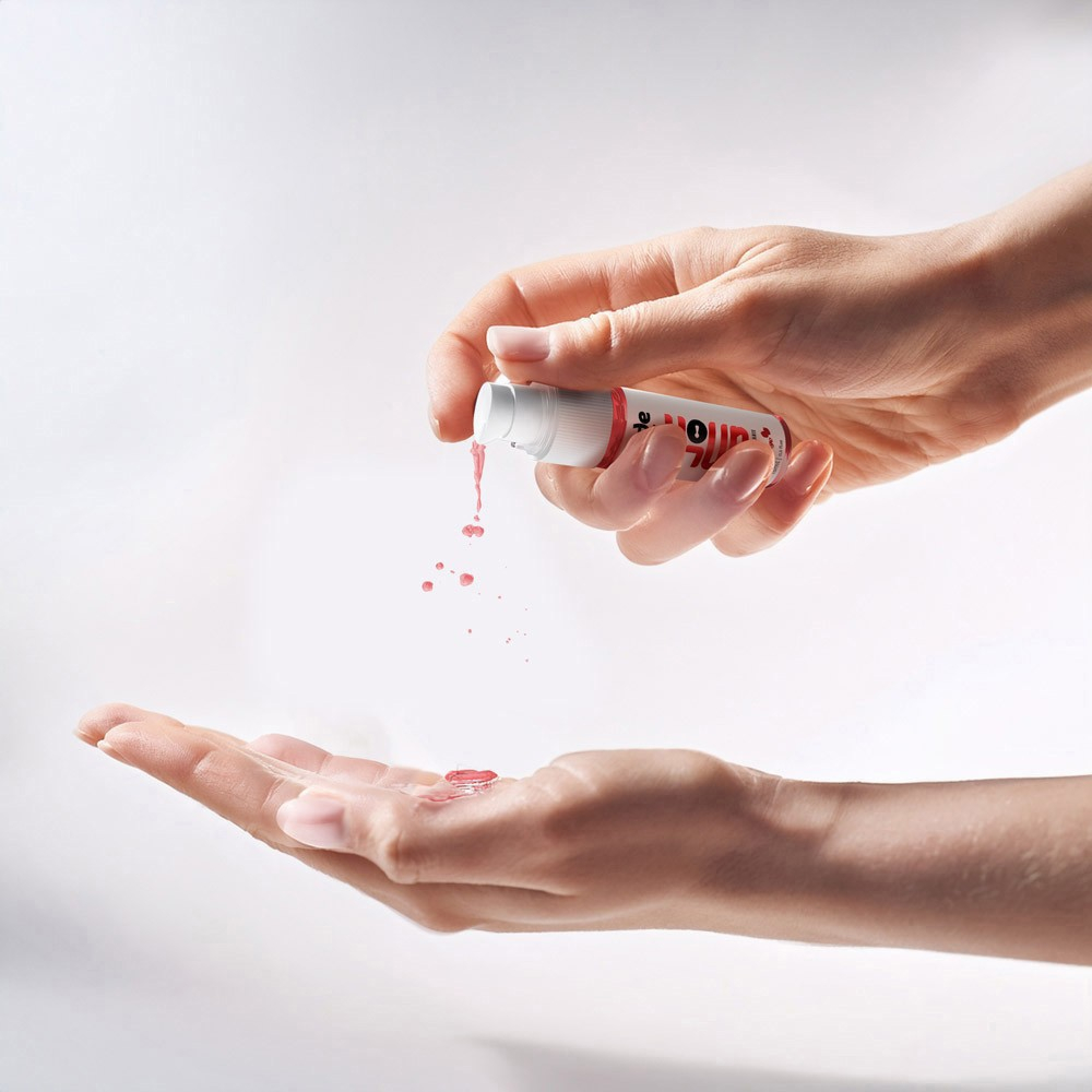M�os aplicando o gel dessensibilizante Unlok de morango, em frasco de 15ml, na palma da m�o, com fundo claro